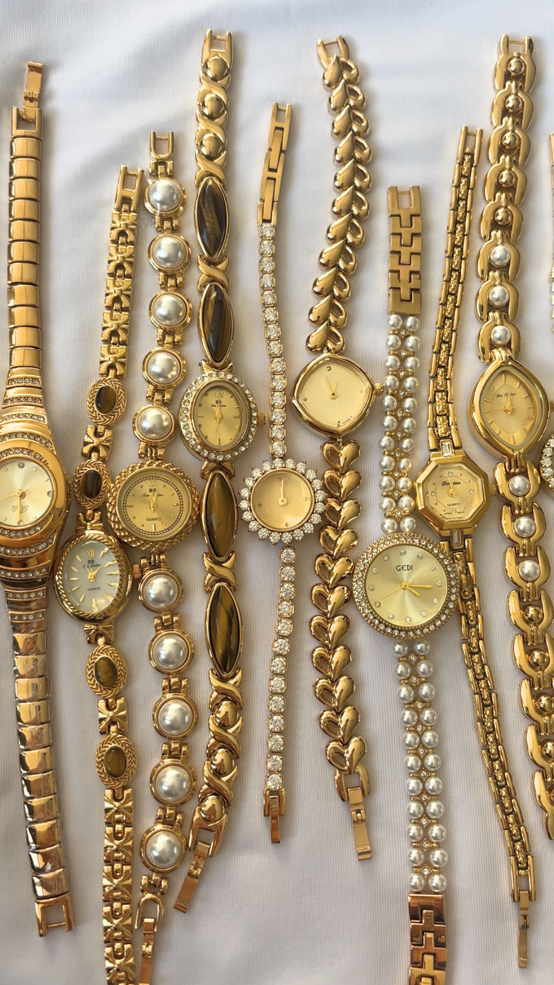 Collection of gold wristwatches and bracelets on a white background