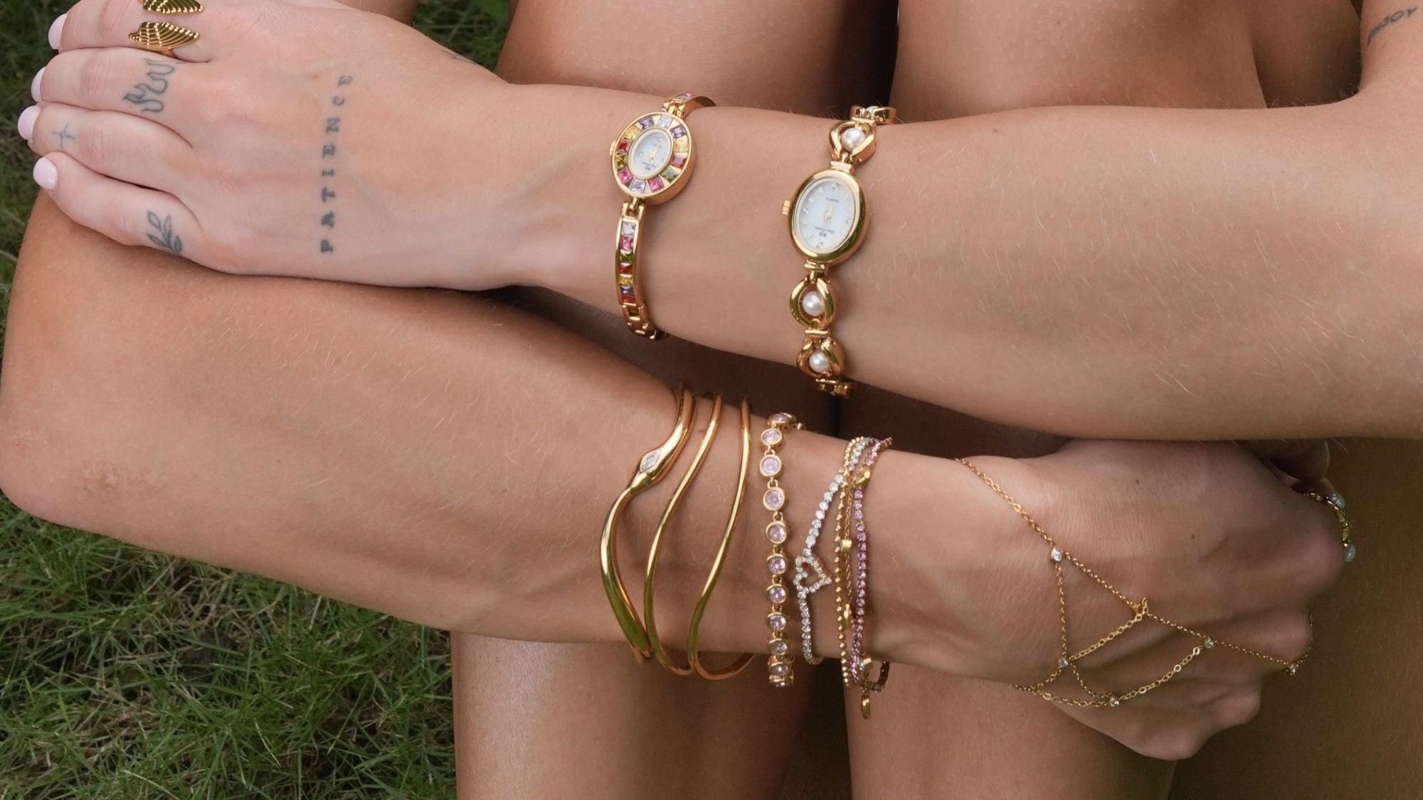 Person wearing multiple gold bracelets on a grassy background
