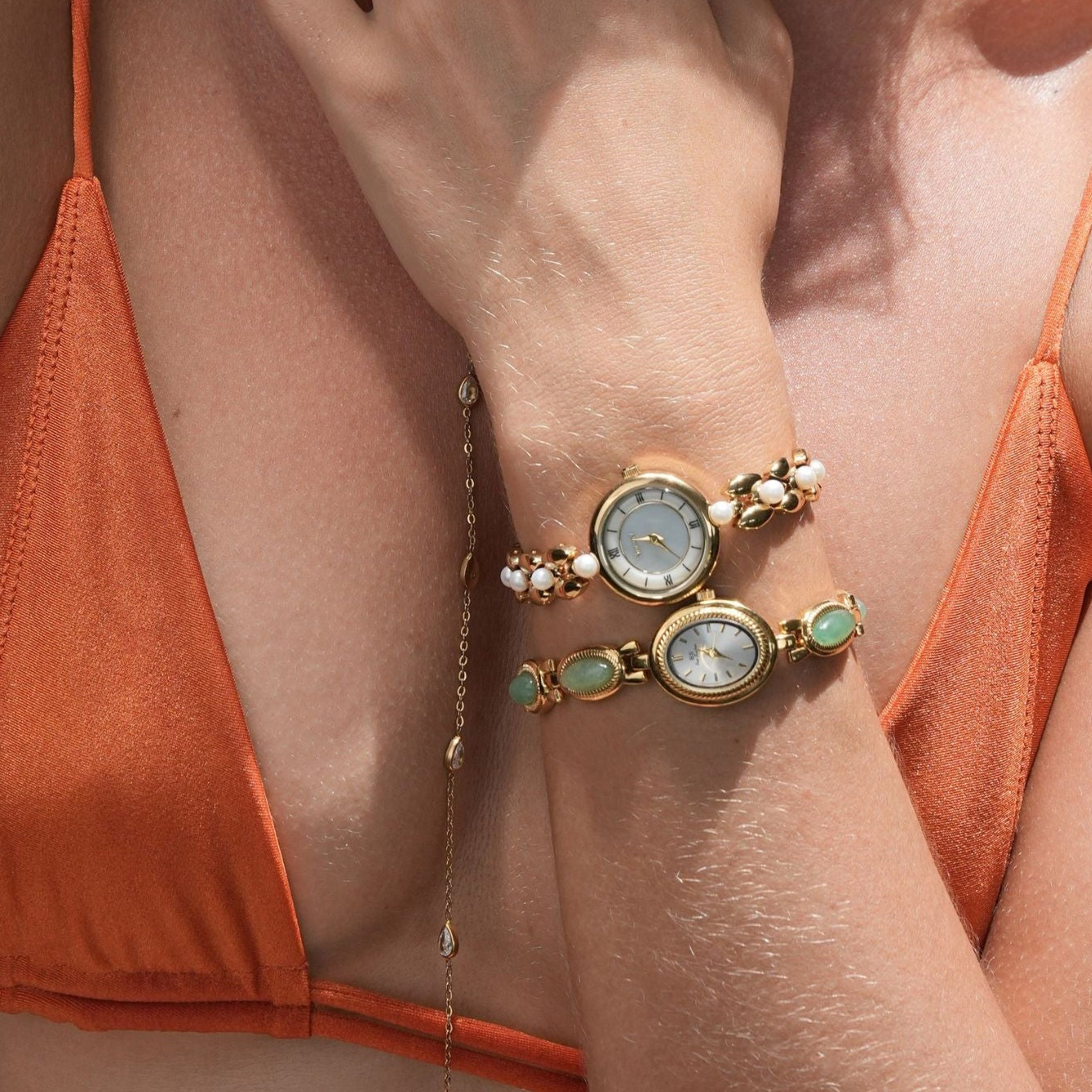 Woman wearing an orange bikini with a close-up of her hand and jewelry.