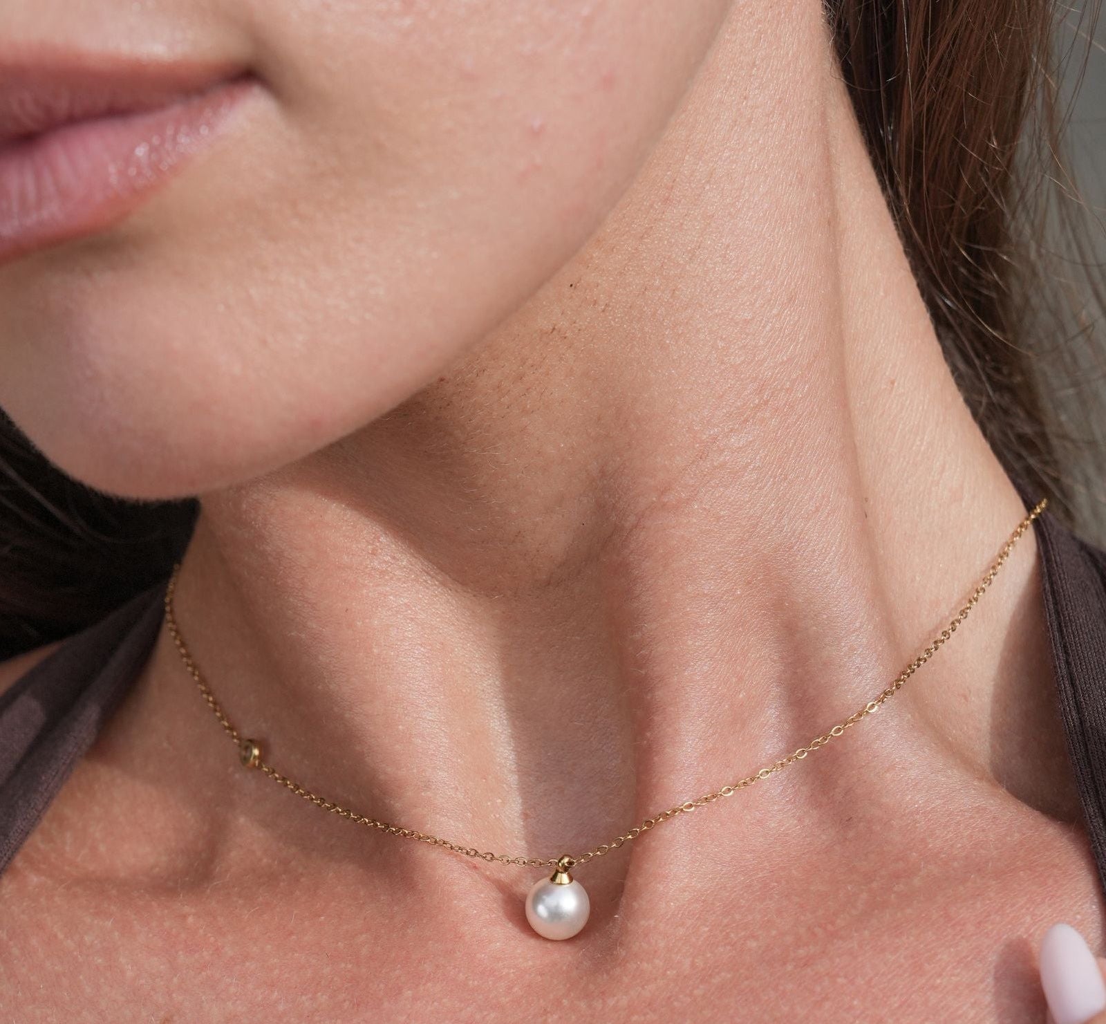 Close-up of a woman wearing pearl earrings and a necklace.